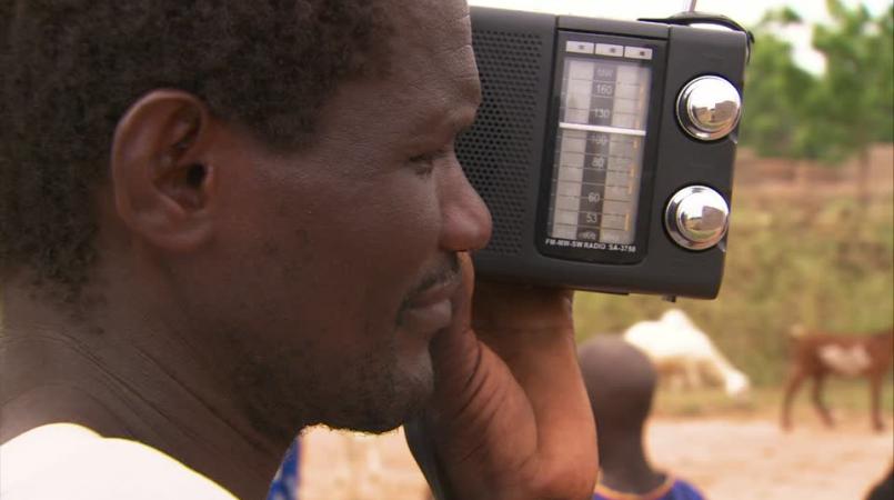 Un homme tenant une radio près de son oreille.