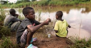 Deux garçons et un homme pêchent dans une rivière à Mtandile à Lilongwe, une zone fortement touchée par l'épidémie de choléra en raison du manque d'eau potable.