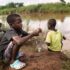 Deux garçons et un homme pêchent dans une rivière à Mtandile à Lilongwe, une zone fortement touchée par l'épidémie de choléra en raison du manque d'eau potable.