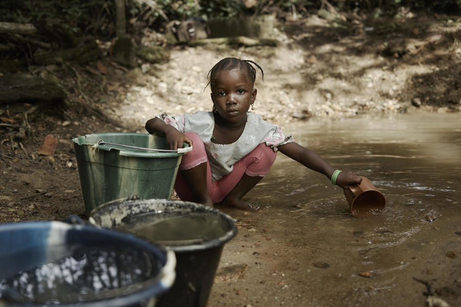 Une fillette remplissant ses récipients dans un petit cours d'eau.